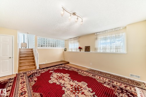 The property features a staircase with wooden treads and a white railing, a white door, and a wall with decorative glass blocks - 11532 9 Avenue, Edmonton, AB - Indoor Photo Showing Other Room
