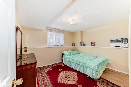 This room features light-colored walls and a window with white curtains - 11532 9 Avenue, Edmonton, AB - Indoor Photo Showing Bedroom