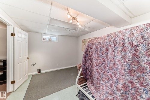 This room features light gray walls, a drop ceiling with track lighting, and a window for natural light - 11532 9 Avenue, Edmonton, AB - Indoor