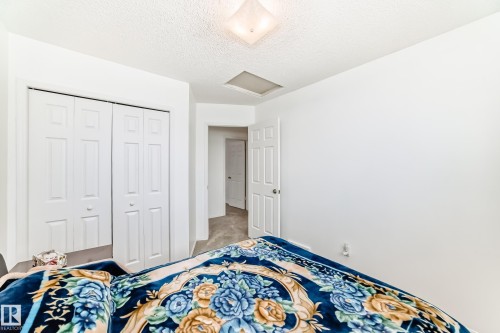 Bedroom featuring white walls, a textured ceiling, a ceiling light fixture, and white bi-fold closet doors - 11532 9 Avenue, Edmonton, AB - Indoor Photo Showing Bedroom