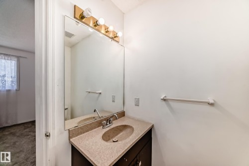 Bathroom vanity with a countertop sink, a large wall mirror, and overhead lighting - 11532 9 Avenue, Edmonton, AB - Indoor Photo Showing Bathroom