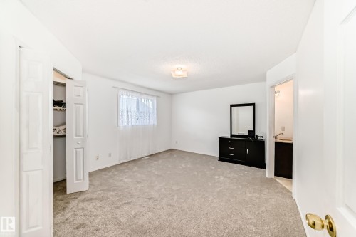 This room features neutral carpeting, white walls, and a window with sheer curtains - 11532 9 Avenue, Edmonton, AB - Indoor Photo Showing Other Room