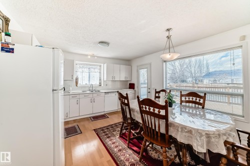This kitchen and dining area features white cabinetry, a refrigerator, and a dishwasher - 11532 9 Avenue, Edmonton, AB - Indoor Photo Showing Dining Room