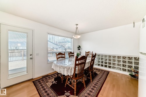 The property features a dining area with hardwood flooring, a glass block accent wall, and a large window providing views of the exterior - 11532 9 Avenue, Edmonton, AB - Indoor Photo Showing Dining Room