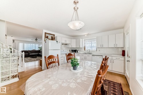 The kitchen features white cabinetry, a white refrigerator, and a window with blinds providing natural light - 11532 9 Avenue, Edmonton, AB - Indoor Photo Showing Dining Room