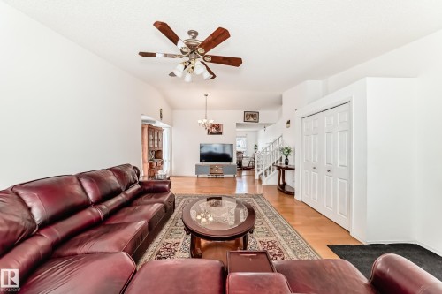 Living area featuring light wood flooring, a ceiling fan, and a view of the hallway with stairs - 11532 9 Avenue, Edmonton, AB - Indoor Photo Showing Living Room With Fireplace