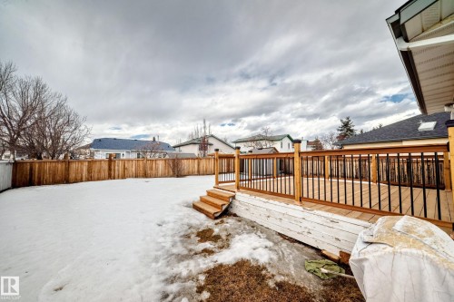 The property features a spacious backyard with a private wooden fence and a newly constructed wooden deck with railings - 11532 9 Avenue, Edmonton, AB - Outdoor