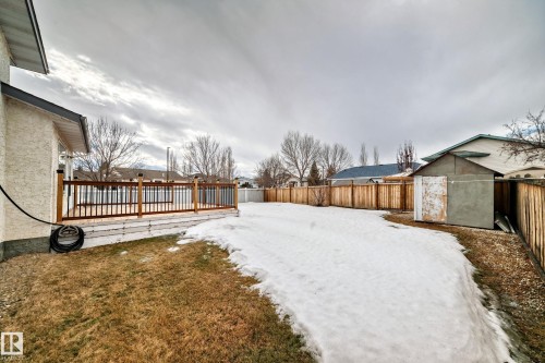 The property features a wooden deck with dark railings, a fenced yard with grass and snow, and a shed - 11532 9 Avenue, Edmonton, AB - Outdoor