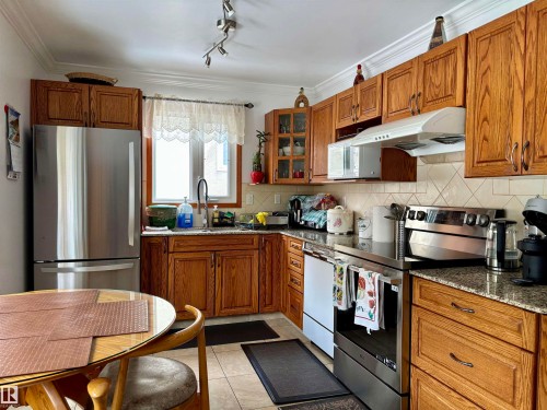 Kitchen with stainless steel appliances, wood finish cabinetry, glass insert cabinets, and ornamental molding - 39 Grand Meadow Crescent, Edmonton, AB - Indoor Photo Showing Kitchen