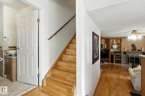 Stairs featuring a ceiling fan, a textured ceiling, wood finished floors, and a fireplace - 39 Grand Meadow Crescent, Edmonton, AB - Indoor Photo Showing Other Room