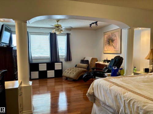 Bedroom with decorative columns, arched walkways, dark wood-style flooring, track lighting, and a textured ceiling - 39 Grand Meadow Crescent, Edmonton, AB - Indoor Photo Showing Bedroom