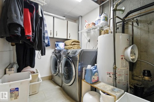 Laundry room with gas water heater, cabinet space, separate washer and dryer, and light tile patterned floors - 39 Grand Meadow Crescent, Edmonton, AB - Indoor Photo Showing Laundry Room