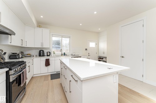 Kitchen featuring a kitchen island, light wood-type flooring, light stone countertops, stainless steel gas range oven, and recessed lighting - 2 11569 University Avenue, Edmonton, AB - Indoor Photo Showing Kitchen