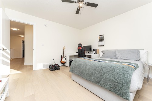 Bedroom featuring light wood-type flooring, ceiling fan, and an office area - 2 11569 University Avenue, Edmonton, AB - Indoor Photo Showing Bedroom