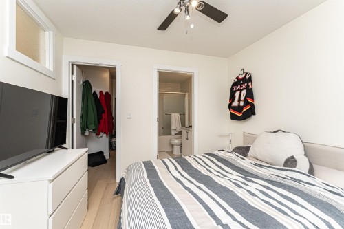 Bedroom featuring light wood finished floors, a walk in closet, a ceiling fan, and connected bathroom - 2 11569 University Avenue, Edmonton, AB - Indoor Photo Showing Bedroom