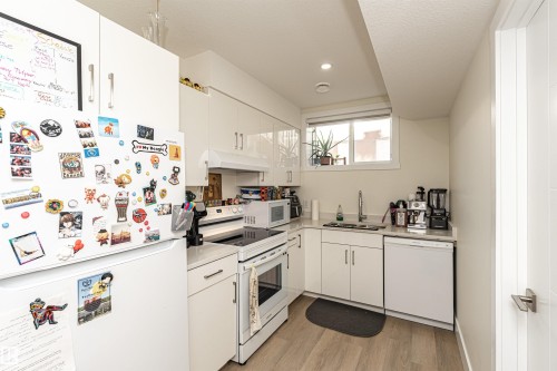 Kitchen featuring white appliances, light countertops, white cabinetry, light wood finished floors, and recessed lighting - 2 11569 University Avenue, Edmonton, AB - Indoor Photo Showing Kitchen