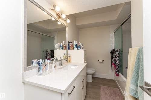 Full bathroom featuring vanity, shower / bath combination with glass door, light wood finished floors, and a textured ceiling - 2 11569 University Avenue, Edmonton, AB - Indoor Photo Showing Bathroom