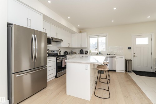 Kitchen featuring stainless steel appliances, a kitchen bar, white cabinetry, tasteful backsplash, and recessed lighting - 2 11569 University Avenue, Edmonton, AB - Indoor Photo Showing Kitchen With Upgraded Kitchen