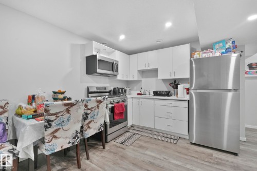 Kitchen featuring stainless steel appliances, light countertops, white cabinets, light wood finished floors, and recessed lighting - 2428 Wonnacott Crest, Edmonton, AB - Indoor Photo Showing Kitchen