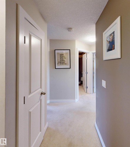 Hallway featuring a textured ceiling and light colored carpet - 8 9535 217 Street, Edmonton, AB - Indoor Photo Showing Other Room