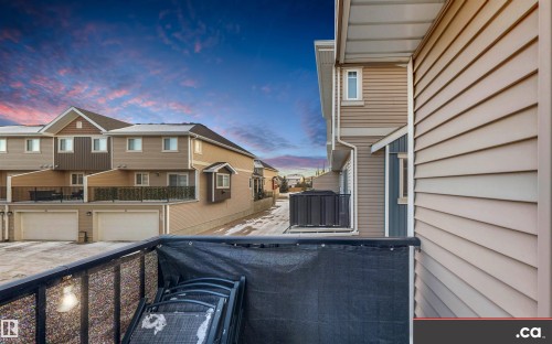 Patio terrace at dusk with a balcony, an attached garage, driveway, and a residential view - 8 9535 217 Street, Edmonton, AB - Outdoor With Exterior
