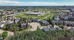Residential neighborhood featuring a mix of detached homes and townhouses, established green spaces with mature trees, and commercial amenities in the distance - 