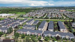 Aerial perspective of a multi-unit residential development featuring numerous townhome-style properties with dark shingle roofing - 