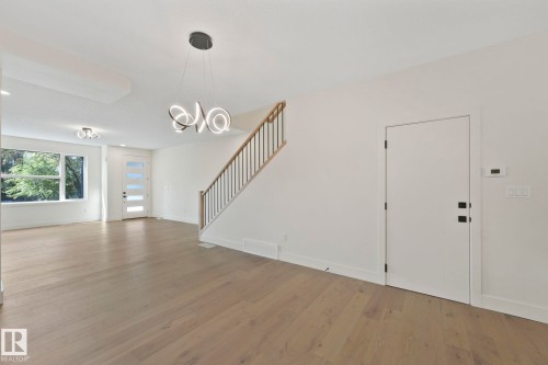 Unfurnished living room featuring light wood finished floors, stairs, and a chandelier - 10965 129 Street, Edmonton, AB - Indoor Photo Showing Other Room
