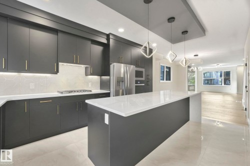 Kitchen featuring decorative light fixtures, a center island, backsplash, modern cabinets, and recessed lighting - 10965 129 Street, Edmonton, AB - Indoor Photo Showing Kitchen With Upgraded Kitchen