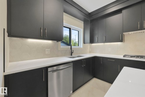 Kitchen with stainless steel appliances, light stone counters, dark cabinetry, decorative backsplash, and modern cabinets - 10965 129 Street, Edmonton, AB - Indoor Photo Showing Kitchen With Double Sink