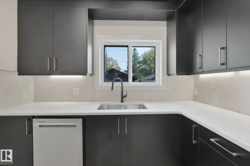 Kitchen featuring modern cabinets, dishwasher, tasteful backsplash, and light stone counters - 10965 129 Street, Edmonton, AB - Indoor Photo Showing Kitchen With Double Sink