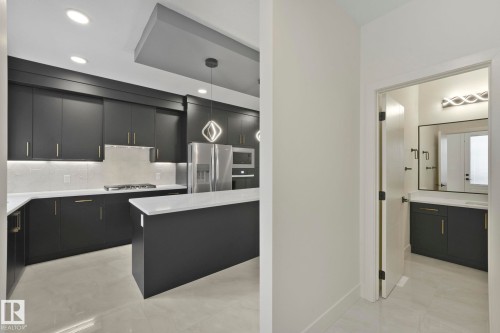 Kitchen featuring dark cabinetry, decorative backsplash, stainless steel appliances, recessed lighting, and decorative light fixtures - 10965 129 Street, Edmonton, AB - Indoor Photo Showing Kitchen With Upgraded Kitchen