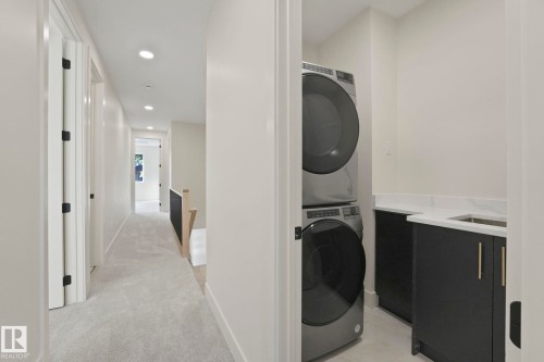 Laundry Upstairs with recessed lighting, stacked washer and dryer, sink and cabinet space. - 10965 129 Street, Edmonton, AB - Indoor Photo Showing Laundry Room