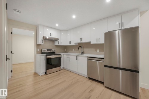 Kitchen with white cabinets, appliances with stainless steel finishes, light wood finished floors, recessed lighting, and under cabinet range hood - 10965 129 Street, Edmonton, AB - Indoor Photo Showing Kitchen