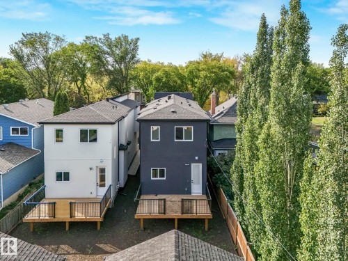 Back of house featuring a fenced backyard, roof with shingles, stucco siding, and view of wooded area - 10965 129 Street, Edmonton, AB - Outdoor