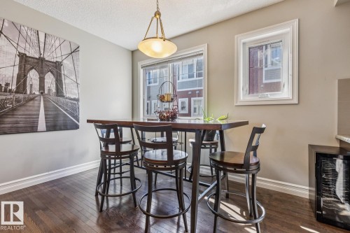 Dining space with wine cooler, dark wood-type flooring, and a textured ceiling - 5409 3 Avenue, Edmonton, AB - Indoor Photo Showing Dining Room