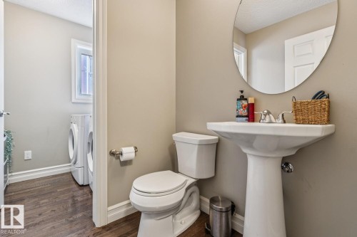 Half bathroom with washing machine and clothes dryer, dark wood-style flooring, and a textured ceiling - 5409 3 Avenue, Edmonton, AB - Indoor Photo Showing Bathroom