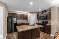 Kitchen with black appliances, dark brown cabinets, dark wood-style flooring, a center island with sink, and a textured ceiling - 