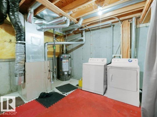 Laundry area featuring heating unit, water heater, unfinished concrete flooring, and washing machine and clothes dryer - 196 230 Edwards Drive, Edmonton, AB - Indoor Photo Showing Laundry Room