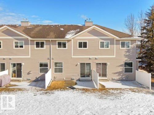Snow covered back of property featuring a patio and a chimney - 196 230 Edwards Drive, Edmonton, AB - Outdoor