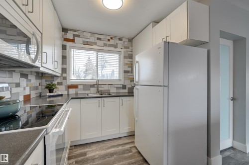 Kitchen with white appliances, tasteful backsplash, light wood-style flooring, and white cabinets - 13932 118 Avenue, Edmonton, AB - Indoor Photo Showing Kitchen With Double Sink
