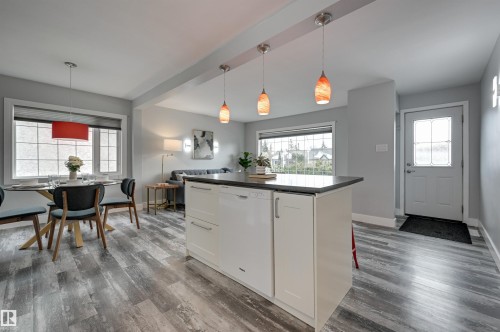 Kitchen featuring white cabinets, dishwasher, dark countertops, decorative light fixtures, and dark wood-style flooring - 13932 118 Avenue, Edmonton, AB - Indoor