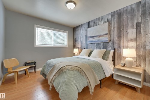 Bedroom with wood walls, an accent wall, and light wood-style floors - 13932 118 Avenue, Edmonton, AB - Indoor Photo Showing Bedroom