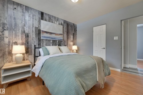 Bedroom with wood walls, an accent wall, and light wood-style floors - 13932 118 Avenue, Edmonton, AB - Indoor Photo Showing Bedroom
