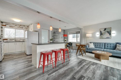 Kitchen featuring white cabinets, white appliances, pendant lighting, a breakfast bar, and dark countertops - 13932 118 Avenue, Edmonton, AB - Indoor