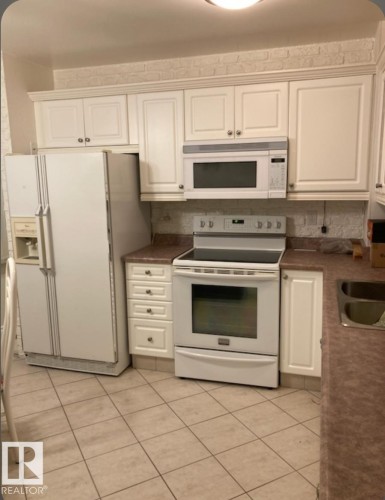 The kitchen features white cabinetry, a white refrigerator, a white microwave, and a white oven - 5404 146 Avenue Nw, Edmonton, AB - Indoor Photo Showing Kitchen