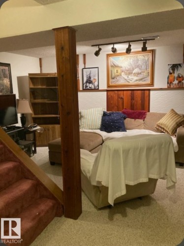 This versatile space features carpeting, a wooden support beam, and track lighting - 5404 146 Avenue Nw, Edmonton, AB - Indoor Photo Showing Bedroom