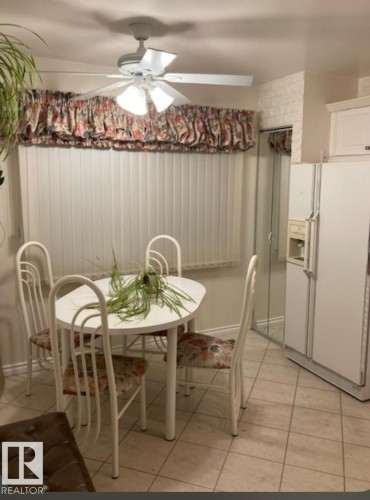 The property features a kitchen dining area with tile flooring, a window with vertical blinds and a floral valance, and a ceiling fan with integrated lighting - 5404 146 Avenue Nw, Edmonton, AB - Indoor Photo Showing Dining Room