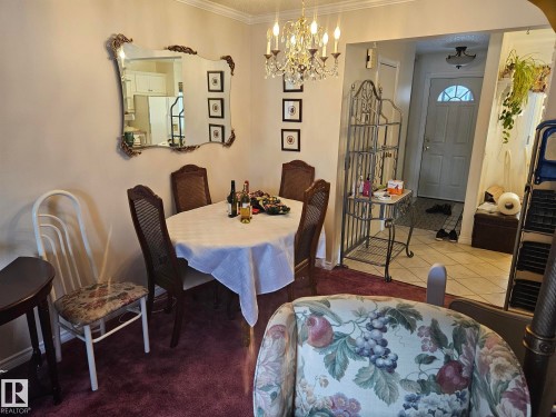 Dining area featuring a chandelier, a decorative mirror, and an entry door with an arched window - 5404 146 Avenue Nw, Edmonton, AB - Indoor Photo Showing Dining Room
