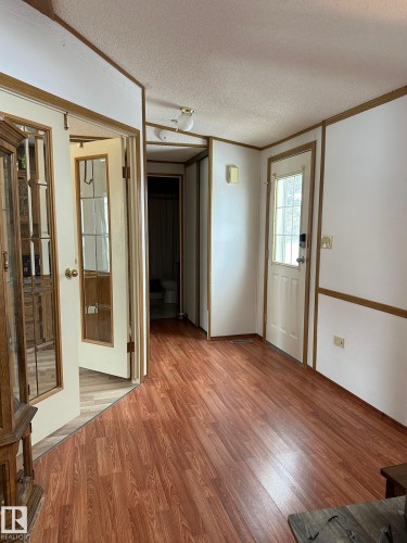 This interior space features wood-look flooring and white walls with wood trim details - 67 4204 47 Street, Wetaskiwin, AB - Indoor Photo Showing Other Room